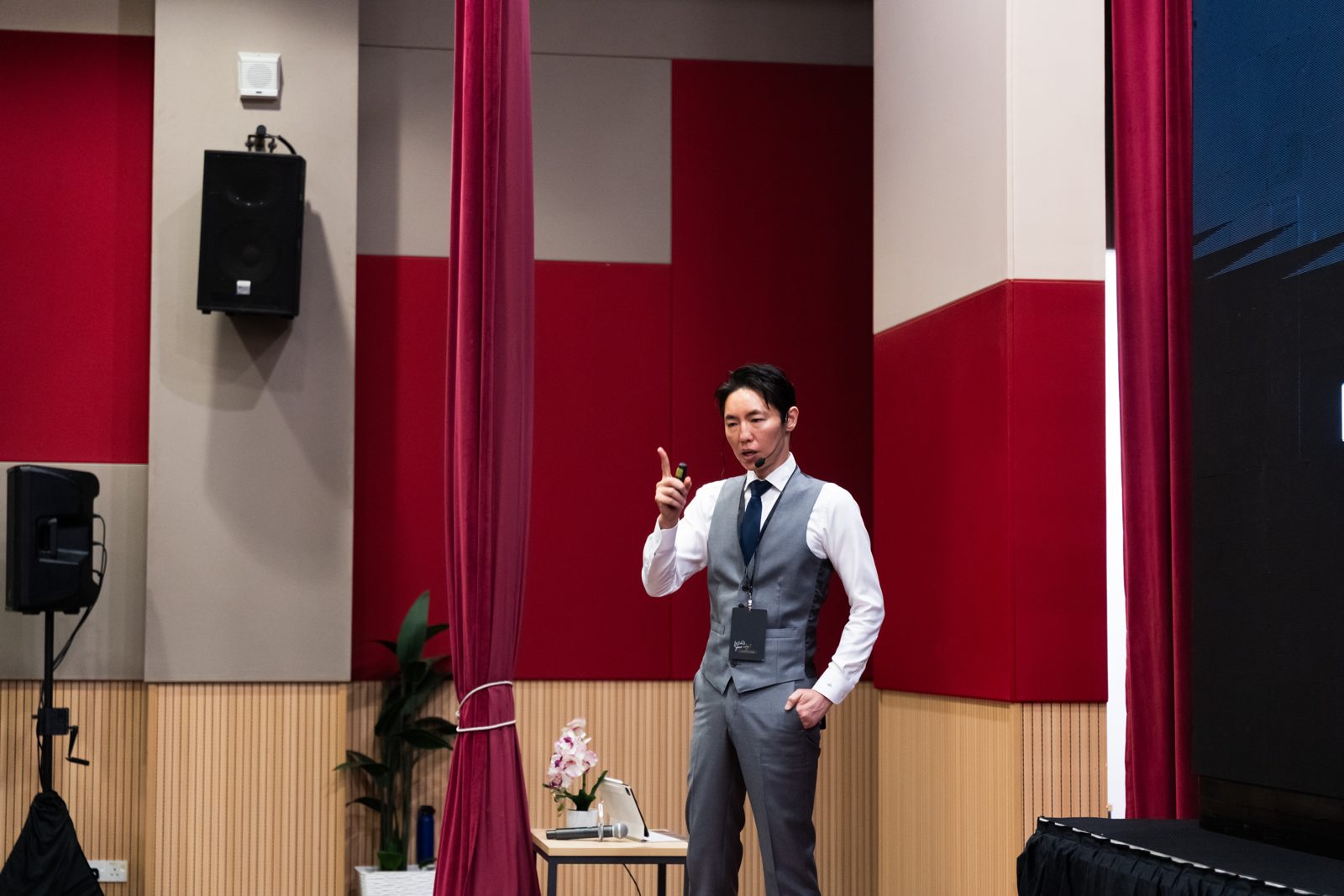 舞台上で指を立てて説明する奥謙太郎院長