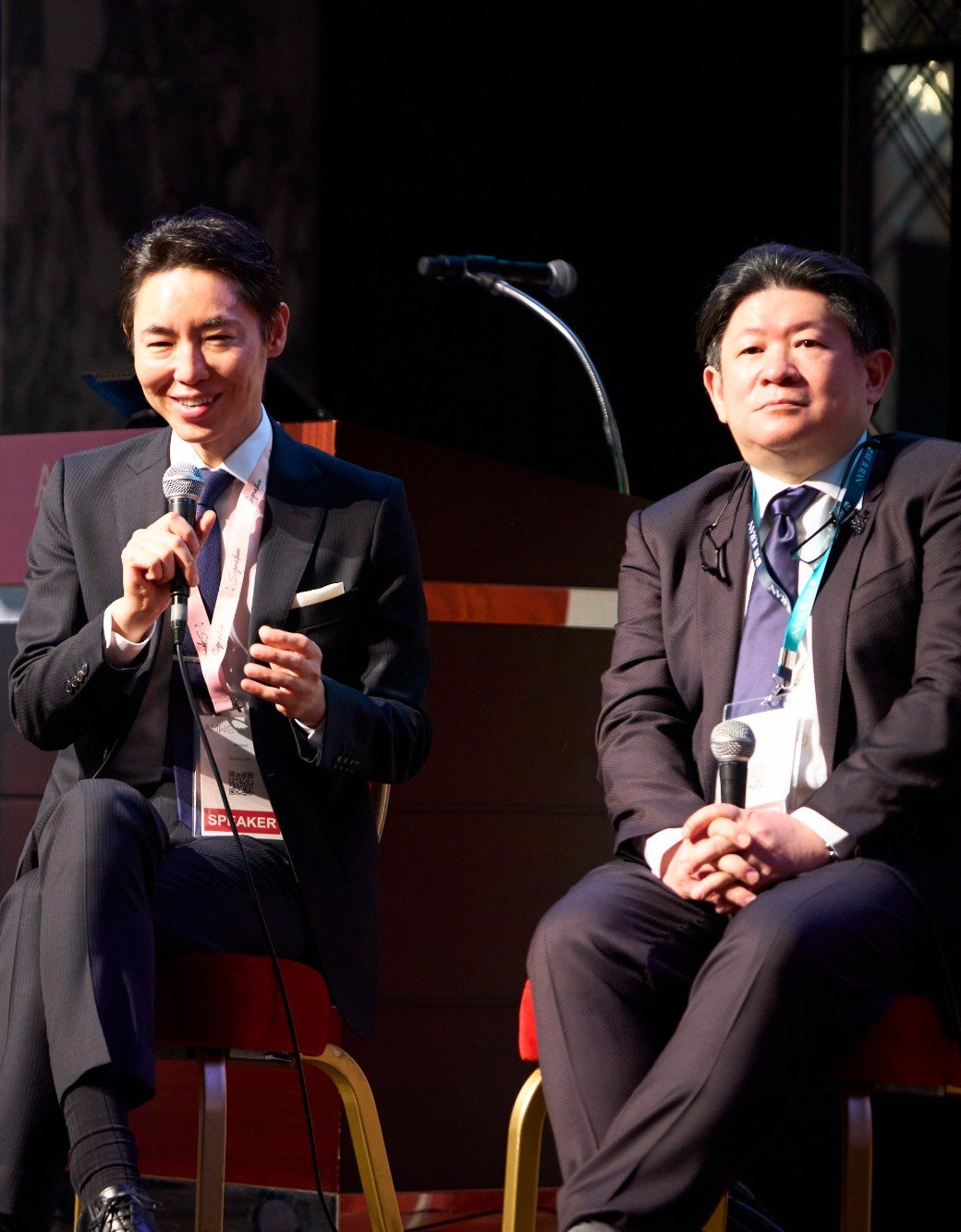 AMWC JAPAN 2026の色素治療のセッションで、マイクを持って話すヒルズグレイスクリニック院長 奥謙太郎